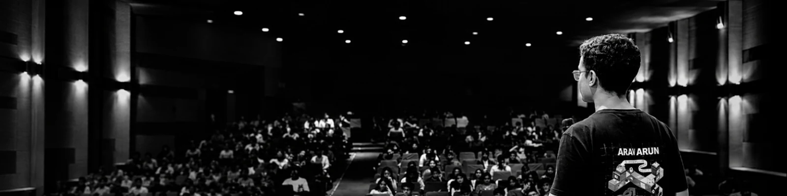 Arav Arun speaking to a theatre audience.
